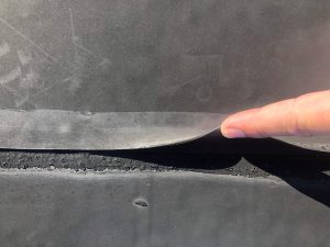 Seams on a rubber roof are showing signs of lost adhesion.