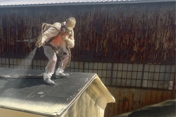 Installer spraying foam on section of roof at Sharpsville Container in PA. 