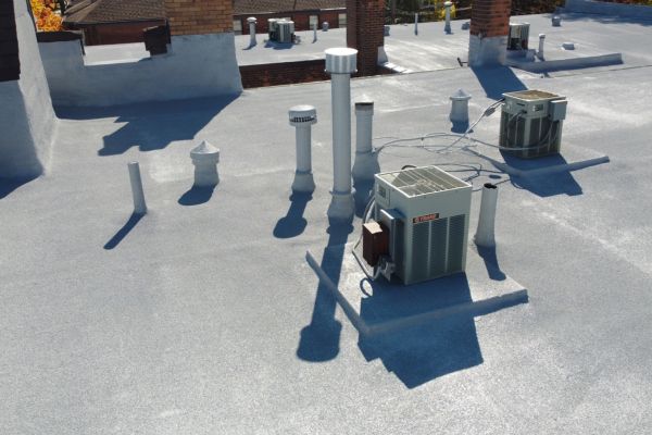 Walls, HVAC unit, and pipes on a finished spray foam roofing system installed at Maryland Court in Michigan.