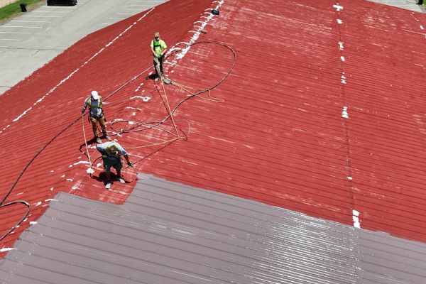 Silicone roof coatings being installed on metal roof in Elyria, Ohio in 2025.